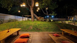 An outdoor dining area with wooden tables and benches, surrounded by a grassy lawn and trees. - Beachfront Condos at Ipioca Beach Life Maceio by MME (Maceió)