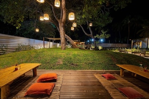 An outdoor dining area with wooden tables and benches, surrounded by a grassy lawn and trees. - Beachfront Condos at Ipioca Beach Life Maceio by MME (Maceió)