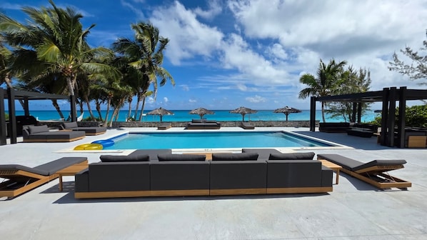 A poolside area with lounge chairs and a view of the ocean.
