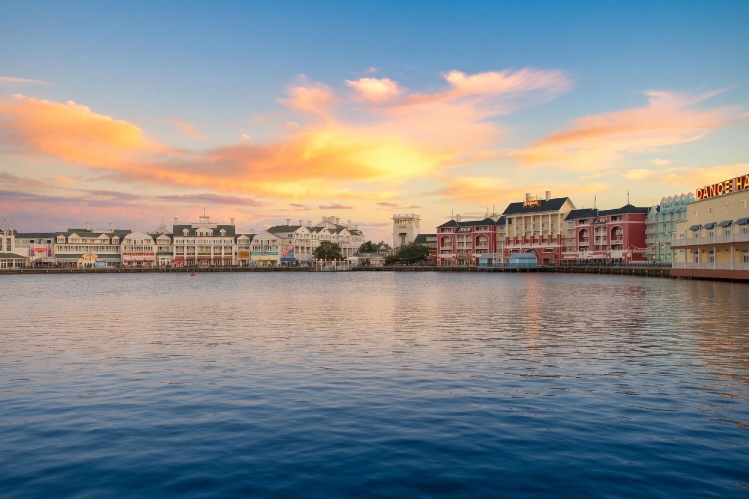 Un hotel sul lungomare con vista sull'acqua e un cielo al tramonto.