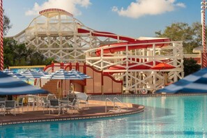 A pool area with a water slide, lounge chairs, and umbrellas. - Orlando | Lively Disney Nights | Pool + Walkable BoardWalk (Lake Buena Vista)