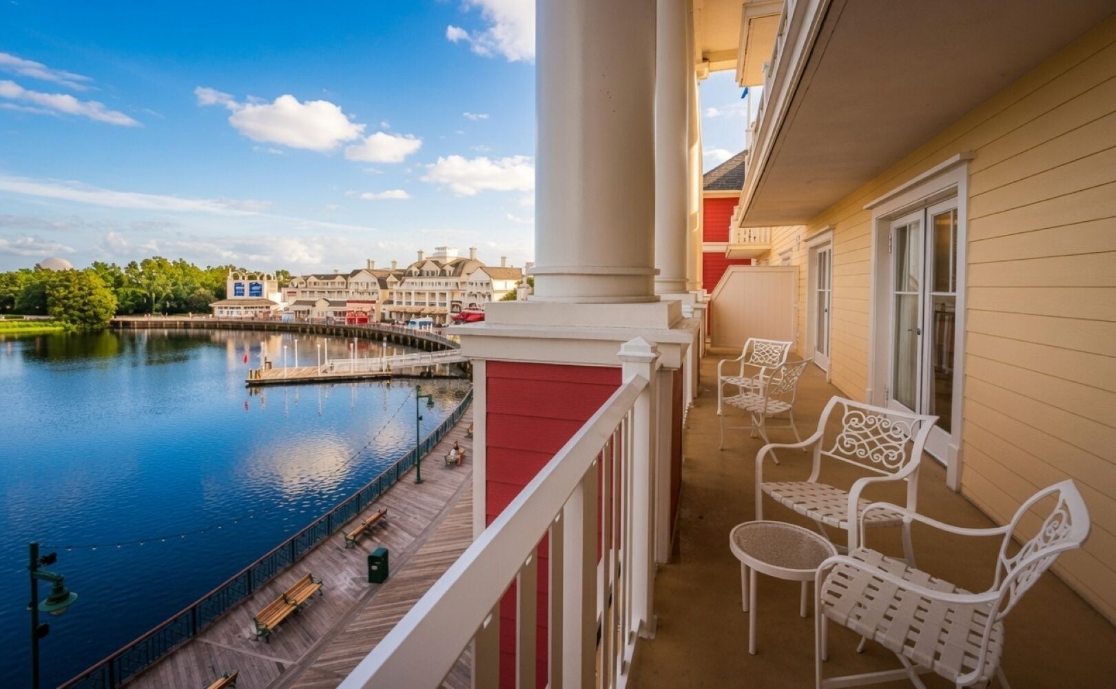 Un balcone con vista su un lago, un'area in legno e mobili da esterno bianchi.