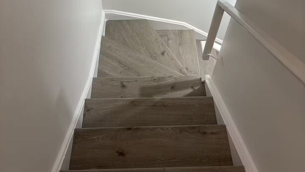Un escalier avec des marches en bois et des murs blancs.