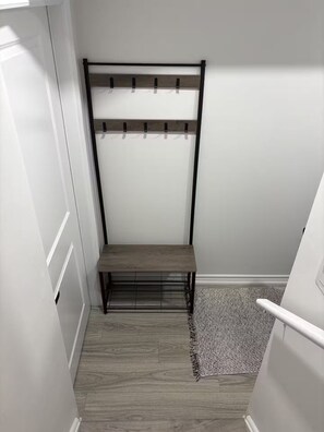 Een smalle gang met een houten bankje en een metalen rek tegen de muur.