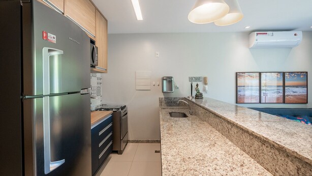 A modern kitchen with stainless steel appliances, granite countertops, and pendant lighting. - Beautiful Apartment Near the Beach Sov0005 (Mata de São João)
