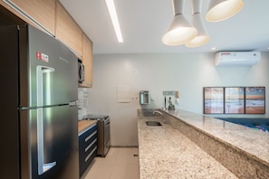 Een moderne keuken met roestvrijstalen apparatuur, granieten aanrechtbladen en hanglampen.