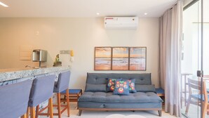 A modern living room with a sofa, chairs, a dining table, and a kitchen area. - Beautiful Apartment Near the Beach Sov0005 (Mata de São João)