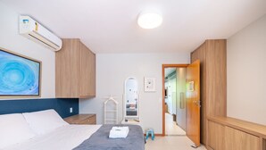 A bedroom with a bed, a wardrobe, a mirror, and an air conditioning unit. - Beautiful Apartment Near the Beach Sov0005 (Mata de São João)