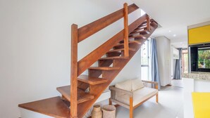 Gradi de fusta en un interior modern, amb una paret blanca, un sofà i una paret d'accent groga.