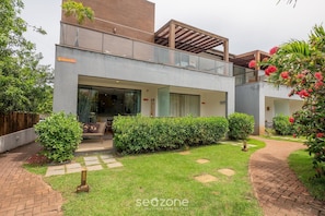 Ein modernes, zweistöckiges Haus mit überdachter Terrasse, einem gepflegten Garten und einem Pflasterweg.