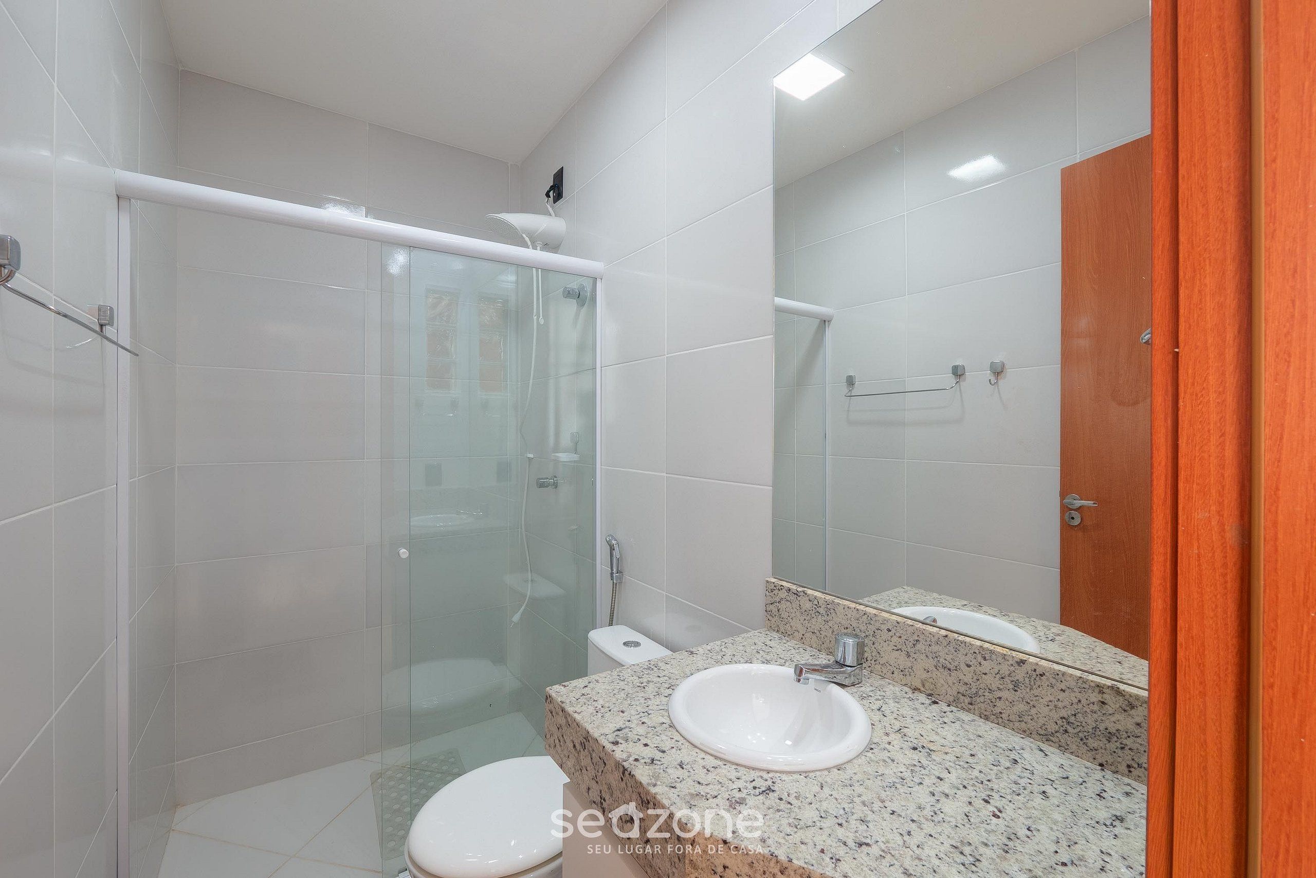 A modern bathroom with a glass shower enclosure, a white sink, and a large mirror.