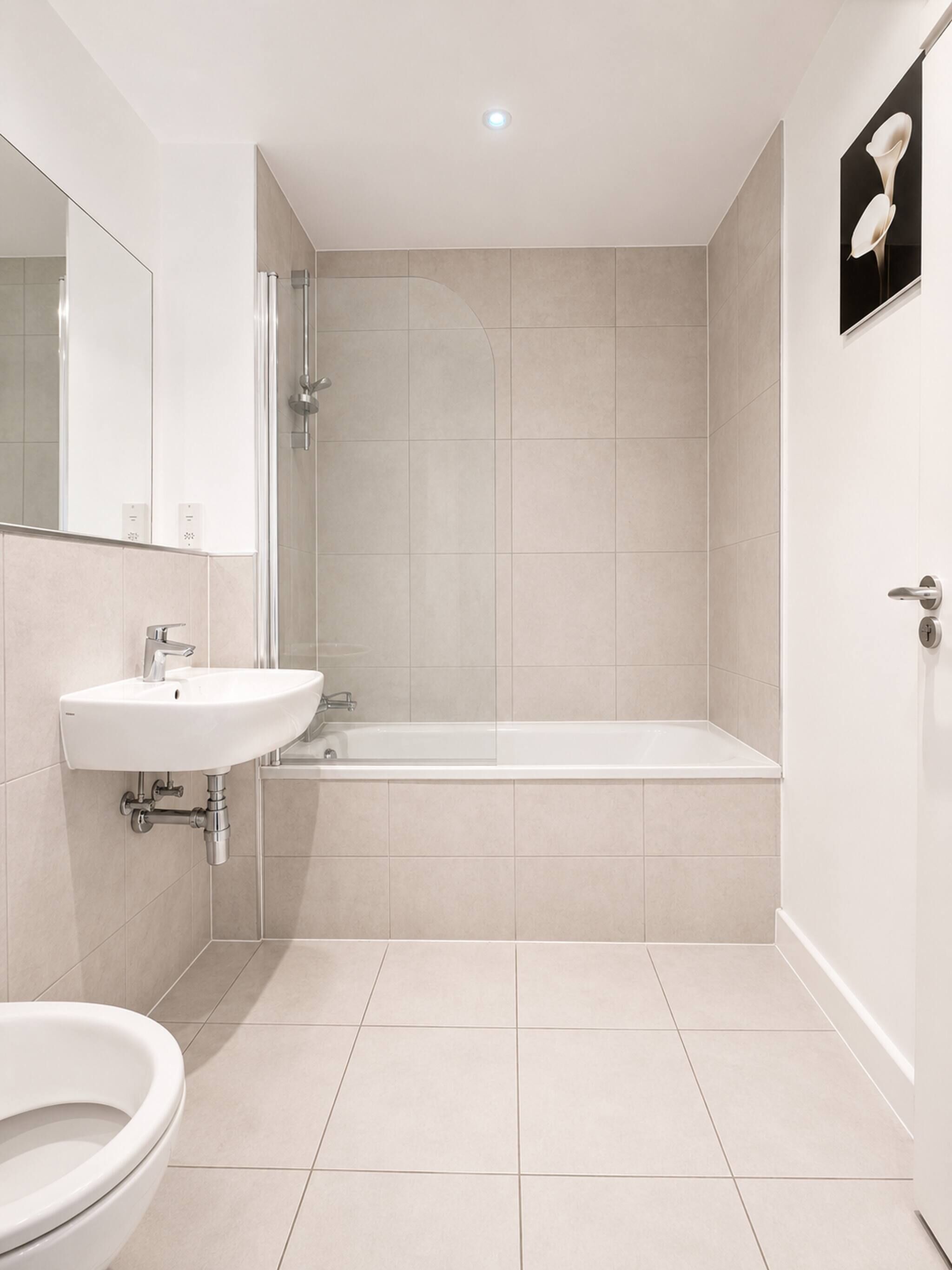 A modern bathroom with a sink, toilet, and bathtub.