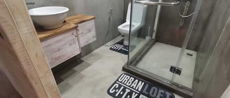 A modern bathroom with a glass-enclosed shower, a white sink, and a wooden vanity.