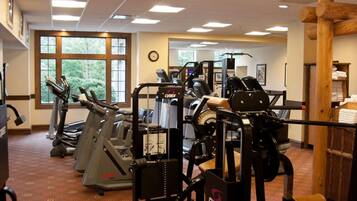 A gym with cardio machines, weightlifting equipment, and a large window with a view of greenery.