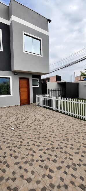 A modern two-story building with a tiled patio, a wooden door, and a white picket fence. - JKLL INN 1980 HOME FULL 15 min from CWB Airport / 5 min from the Botanical Garden  (Curitiba)