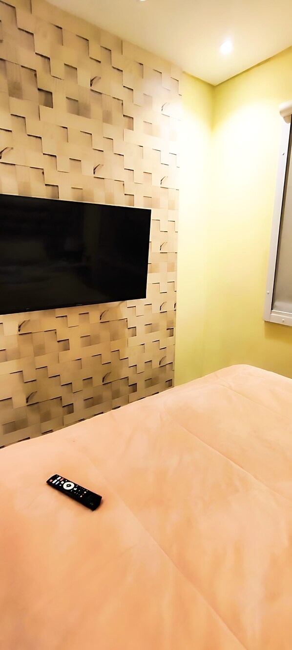 A room with a bed, a wall-mounted TV, and a window.