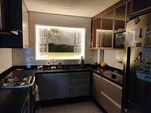 A modern kitchen with a window, stainless steel appliances, and a refrigerator with magnets.