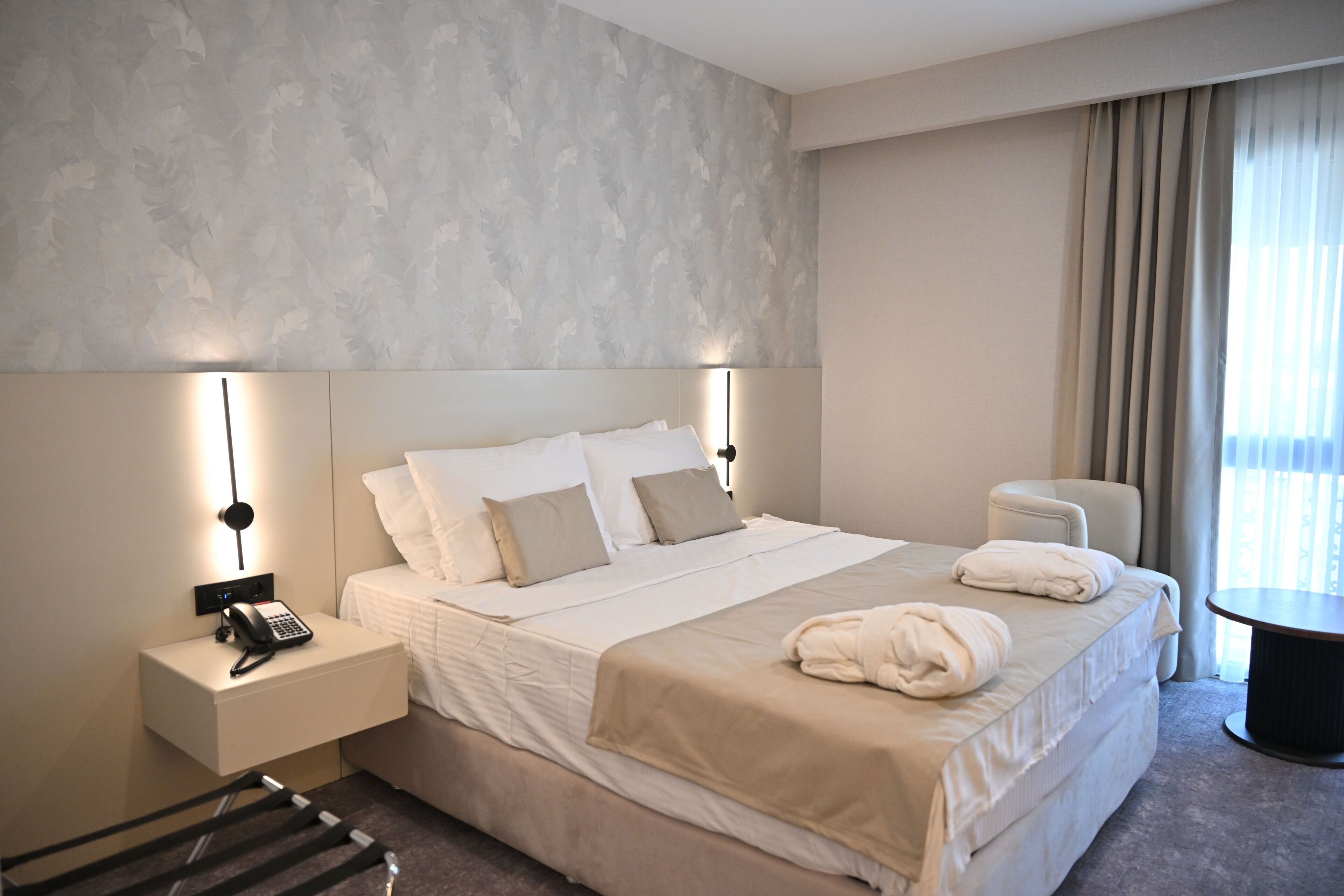 Una habitación de hotel con una cama grande, mesitas de noche, un escritorio y una silla.