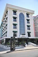 A hotel building with a large arched window, multiple balconies with green awnings, and a sign for 'Janset Boutique Hotel.'