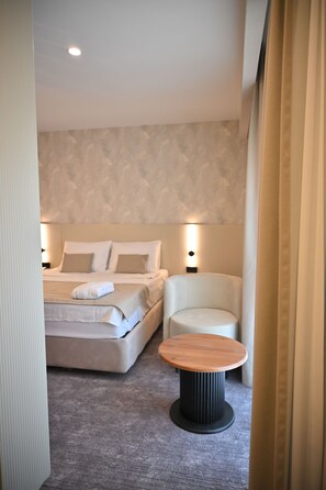 A hotel room with a bed, a chair, a small table, and a wall-mounted light. - Janset Boutique Hotel (Diyarbakır)
