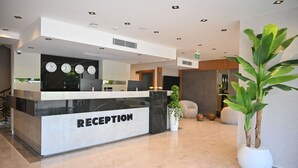 Una recepción con mostrador de mármol, relojes y una planta en maceta.