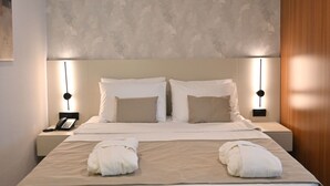 Habitación de hotel con una cama grande, dos lámparas de noche, un teléfono y una pared con diseño de hojas.