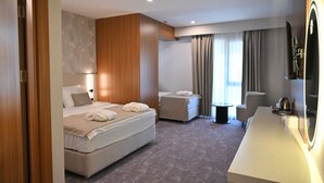 Una habitación de hotel con una cama, un escritorio, una silla y una mesita.