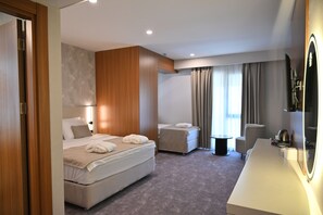 A hotel room with a bed, a desk, a chair, and a small table.