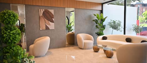 A modern lobby with a large window, a reception desk, and several seating areas.