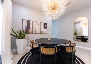 A modern dining area with a round table and four chairs, a potted plant, and a large mirror on the wall. - Brilliant 3-bedroom house with AC in charming Kissimmee (Kissimmee)