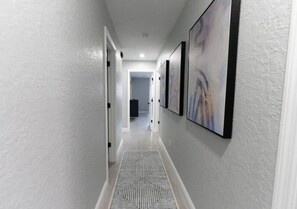 A hallway with a patterned rug, white walls, and framed artwork. - Brilliant 3-bedroom house with AC in charming Kissimmee (Kissimmee)