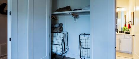 Een inloopkast met planken, een kledingroede en een metalen opbergwagen.