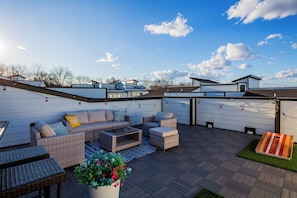 A rooftop patio with outdoor furniture, a potted plant, and string lights. - The Wild West - Nashville: Rooftop Deck (Nashville)