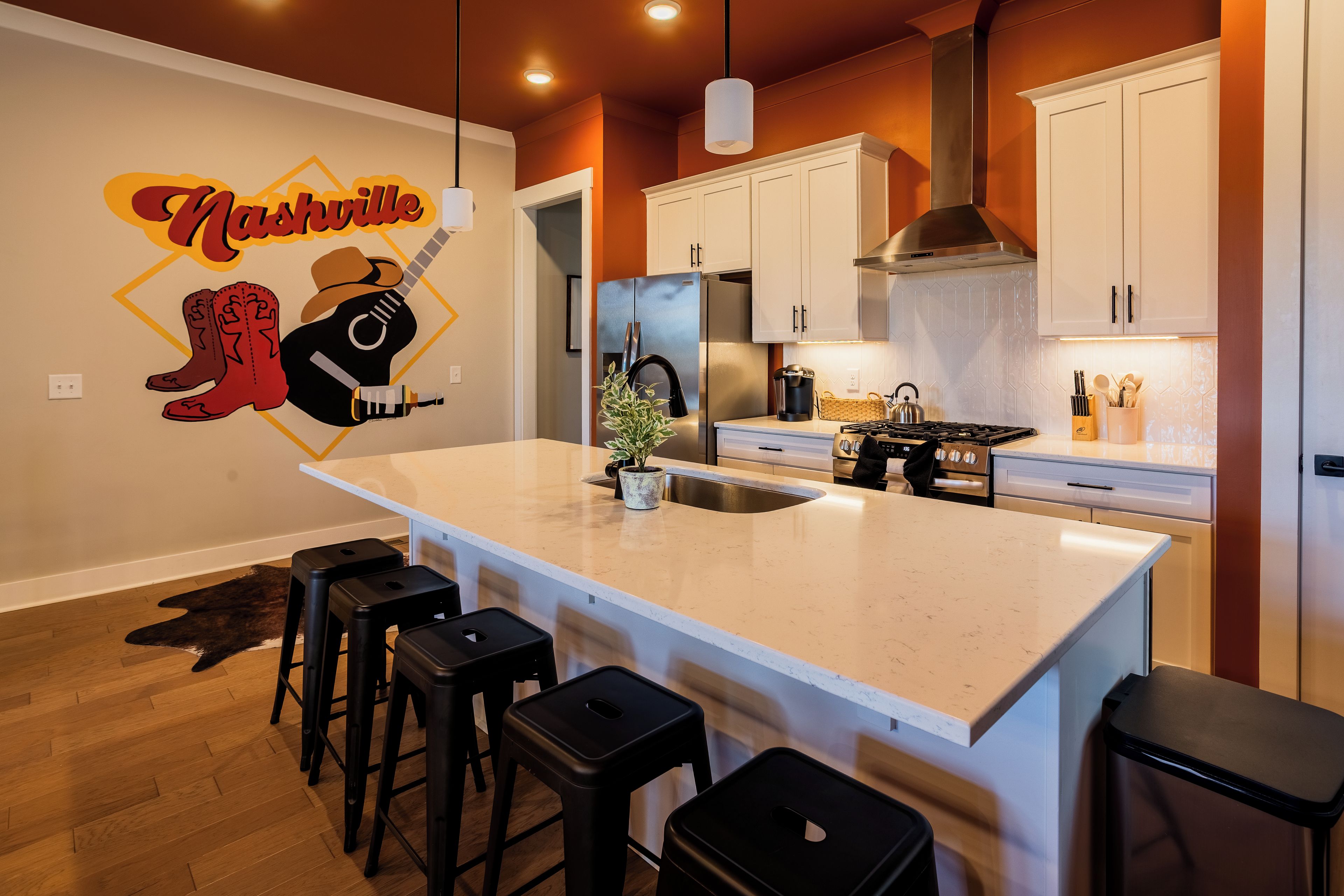 Una cocina moderna con una isla grande, taburetes de bar y una obra de arte con temática de Nashville.