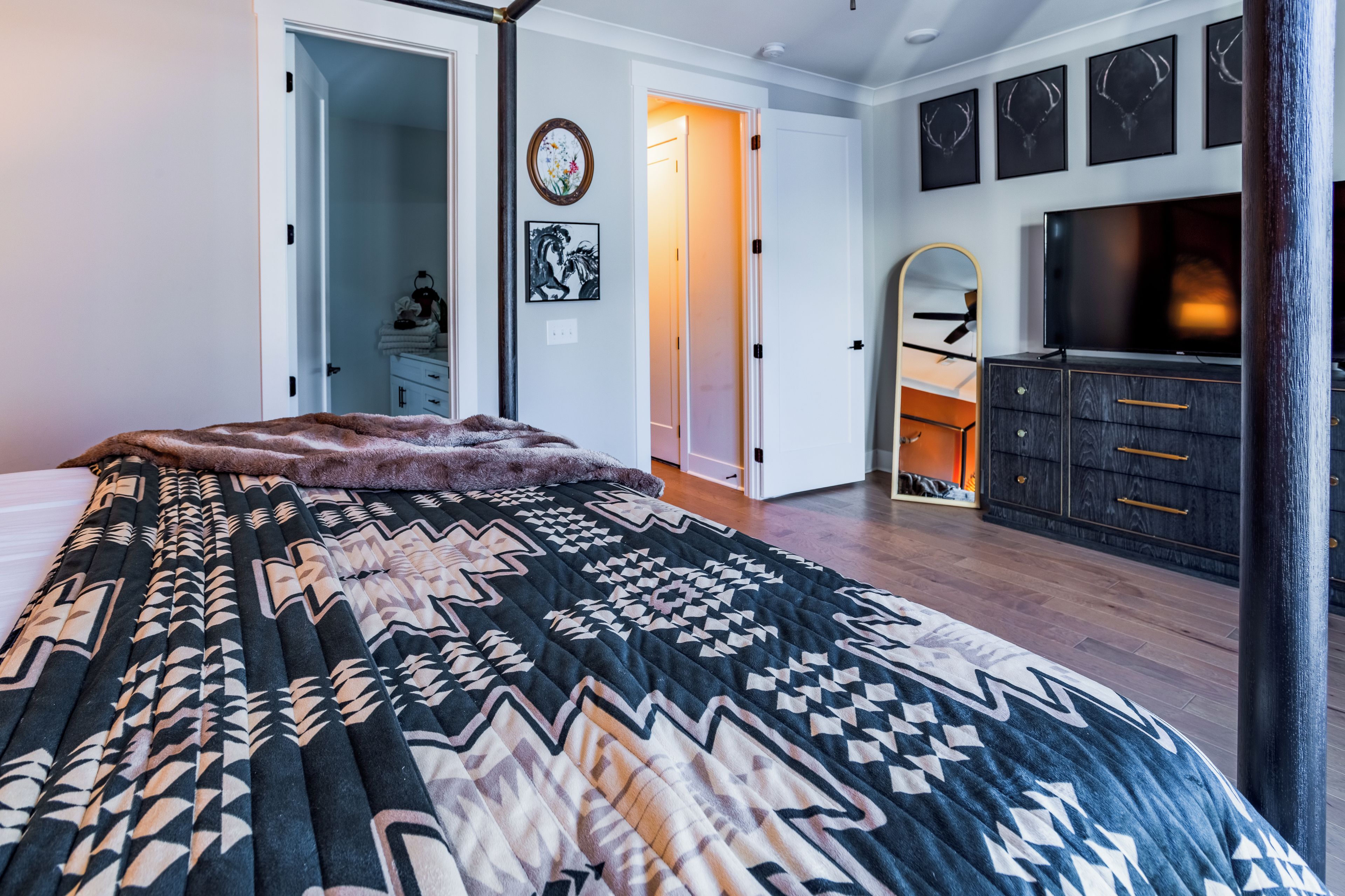 Ein Schlafzimmer mit einem großen Bett, einem Schminktisch, einem Fernseher und einem Spiegel.
