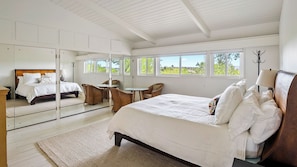 A bedroom with a large bed, a sitting area with chairs, a mirror, and a view of greenery outside. - Above It All by Avantstay Pool + Hot Tub + Fire Pit Hilltop Near Paso (Paso Robles)