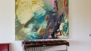 A large abstract painting on a wall, a wooden bench in front of it, and a red chair to the left. - Above It All by Avantstay Pool + Hot Tub + Fire Pit Hilltop Near Paso (Paso Robles)