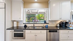 A modern kitchen with stainless steel appliances, a large window, and a view of the outdoors. - Above It All by Avantstay Pool + Hot Tub + Fire Pit Hilltop Near Paso (Paso Robles)