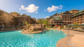 A hotel with a pool, multiple buildings, and a rocky island feature. - Orlando | Family Lodge Retreat | Pool + Resort | 2BR (Lake Buena Vista)