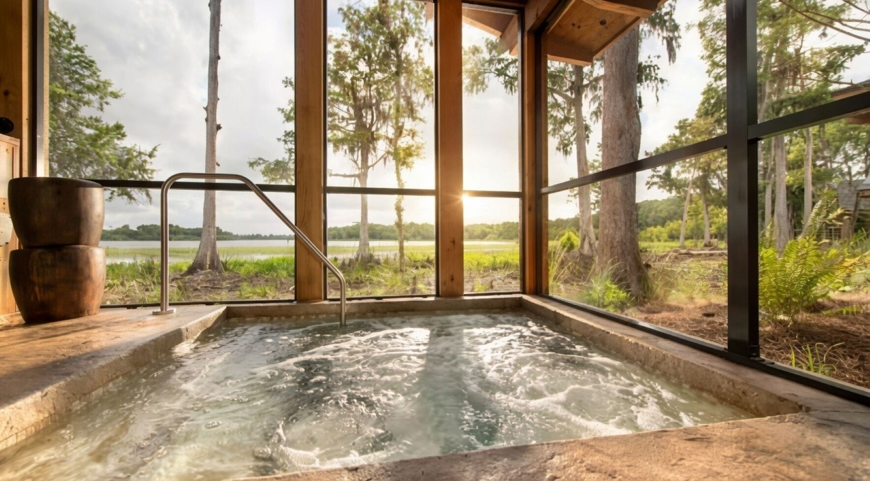 A hot tub with a view of a lake and trees, a wooden bench, and a metal ladder.