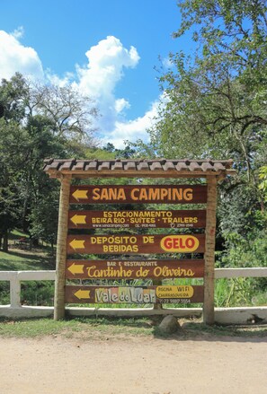 A directional signpost with multiple arrows pointing to various facilities including a camping area, a deposit for food, a restaurant, and a pool.