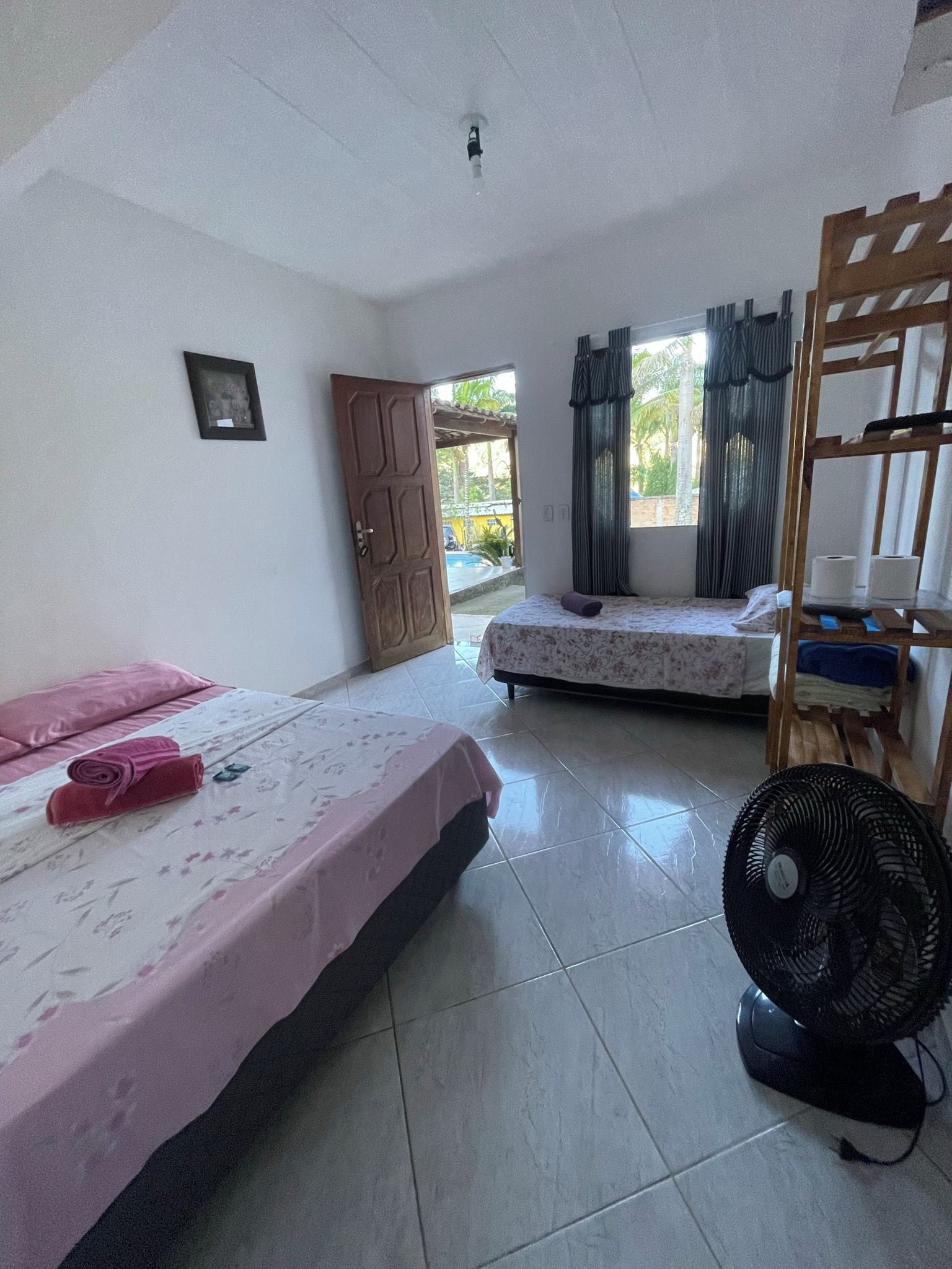 Habitación con dos camas, un ventilador y una puerta que da al exterior.