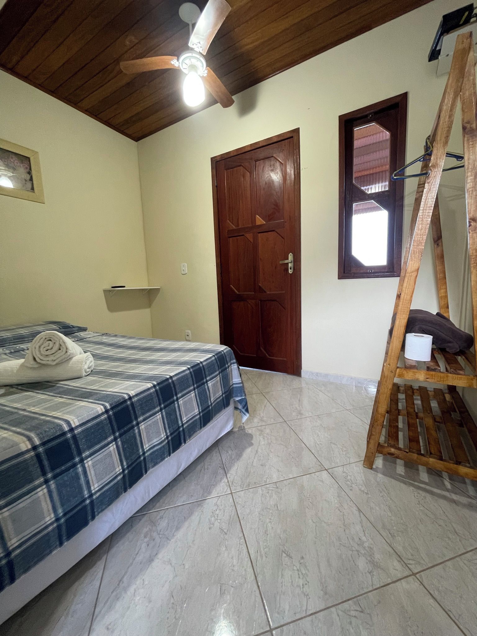 Un dormitorio con cama, una escalera de madera, una puerta y un ventilador de techo.