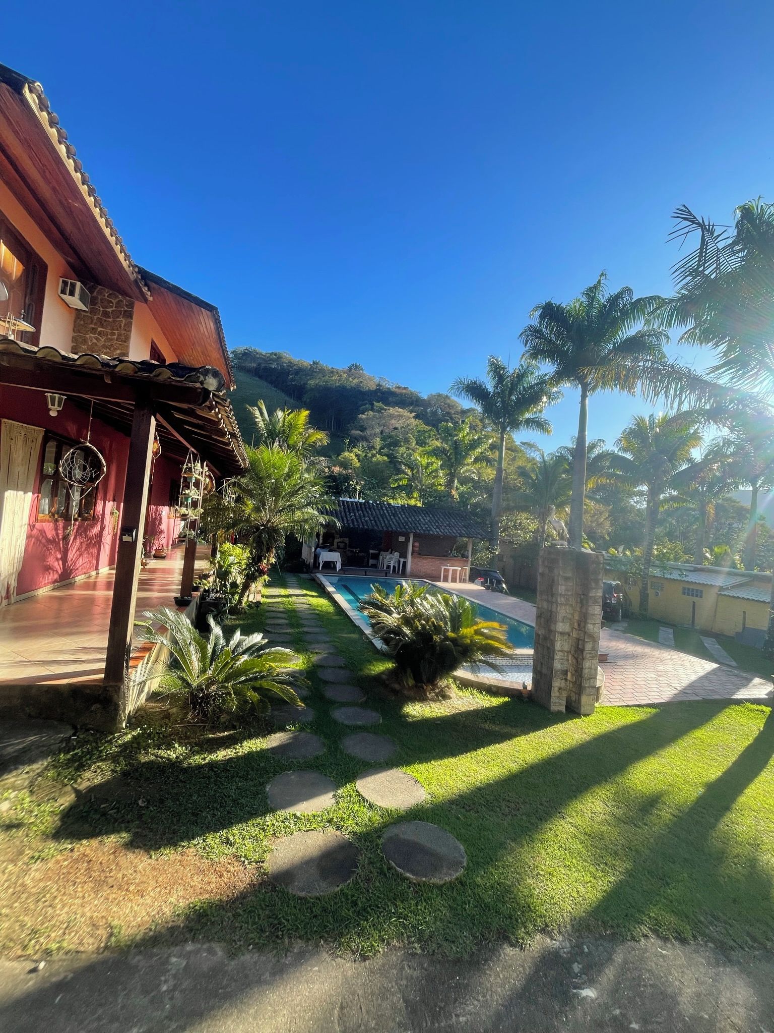 Un patio con piscina, palmeras y un edificio de fachada roja.