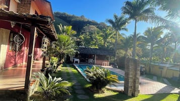 Un patio con piscina, palmeras y un edificio de fachada roja.