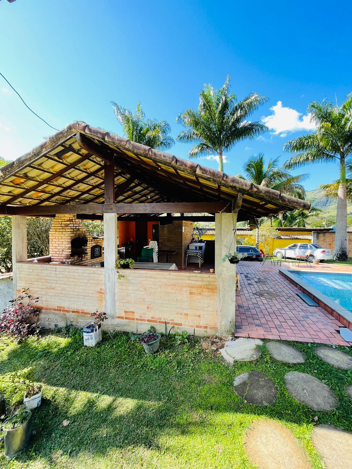 Une petite maison en briques avec un patio couvert, une cheminée en briques et une piscine.