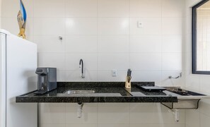 Una cuina moderna amb taulell de granat negre, rentamics d'acer inoxidable i una cafetera.