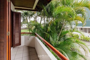 A balcony with a wooden railing, surrounded by lush green palm trees. - Apt 270m From the Beach in Floripa-sc Stcy202 (Florianópolis)