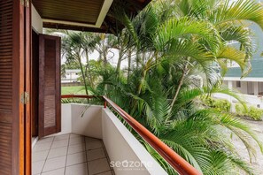 A balcony with a wooden railing, surrounded by lush green palm trees. - Apt 270m From the Beach in Floripa-sc Stcy202 (Florianópolis)