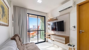 A modern bedroom with a large window, a flat-screen TV, and a sliding door to a balcony. - Apt in Condo w/ Pool & Sea View Sli1013 (Maceió)